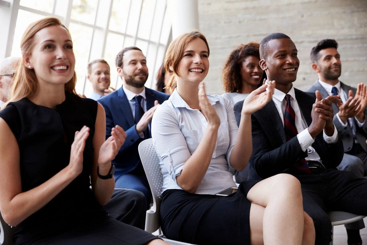 Dimaco business people clapping at a conference.
