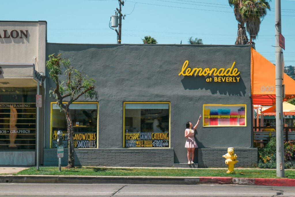 A woman is standing in front of a lemonade shop.