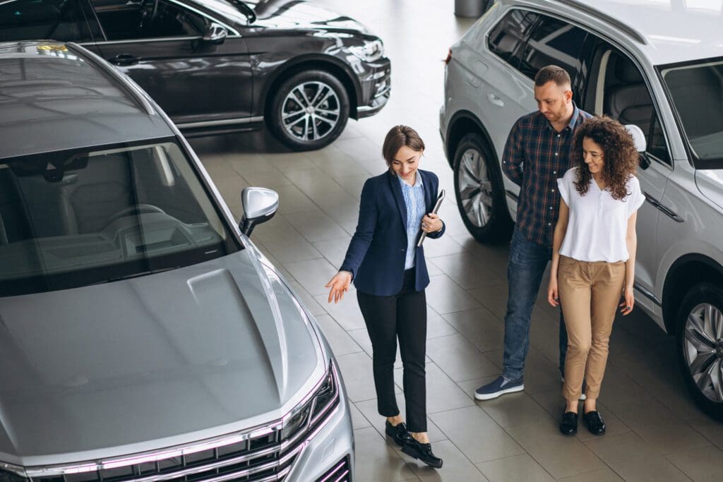 A group of people looking at cars in a showroom.
